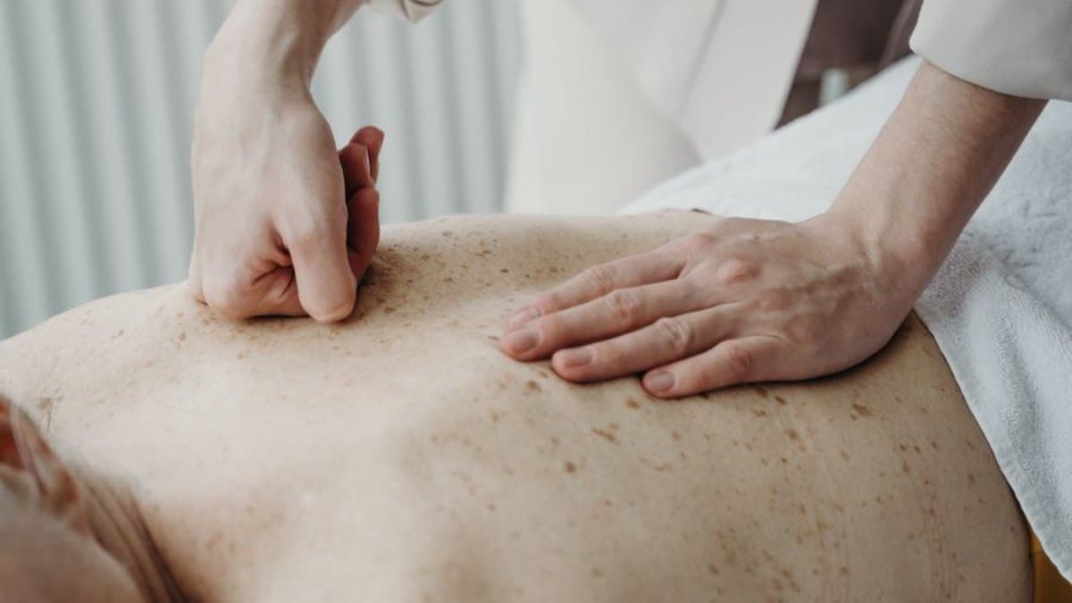 Praticienne massant le haut du dos d'une personne allongée sur une table de soin